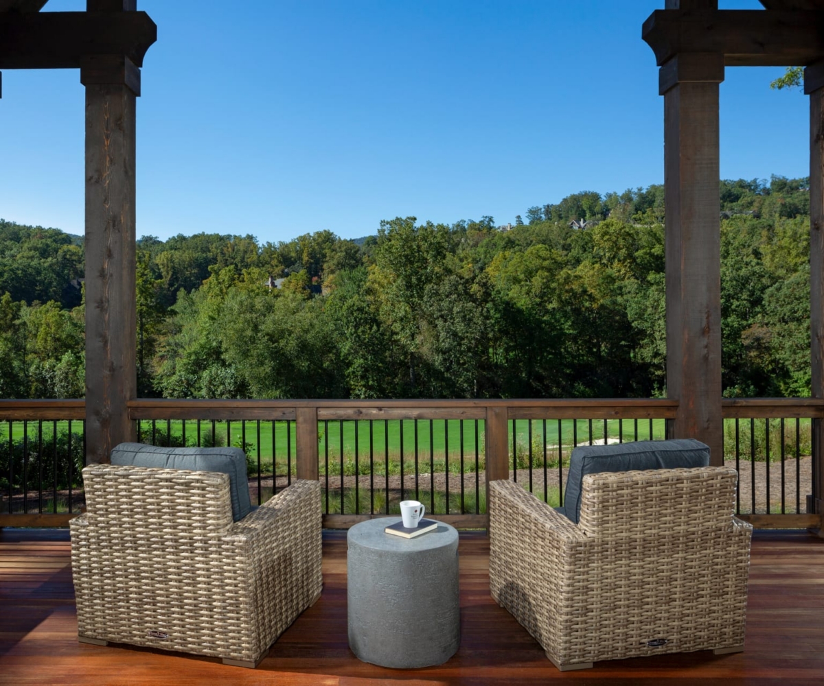 Custom Altamont outdoor living space with two lounge chairs overlooking greenery on wooden porch