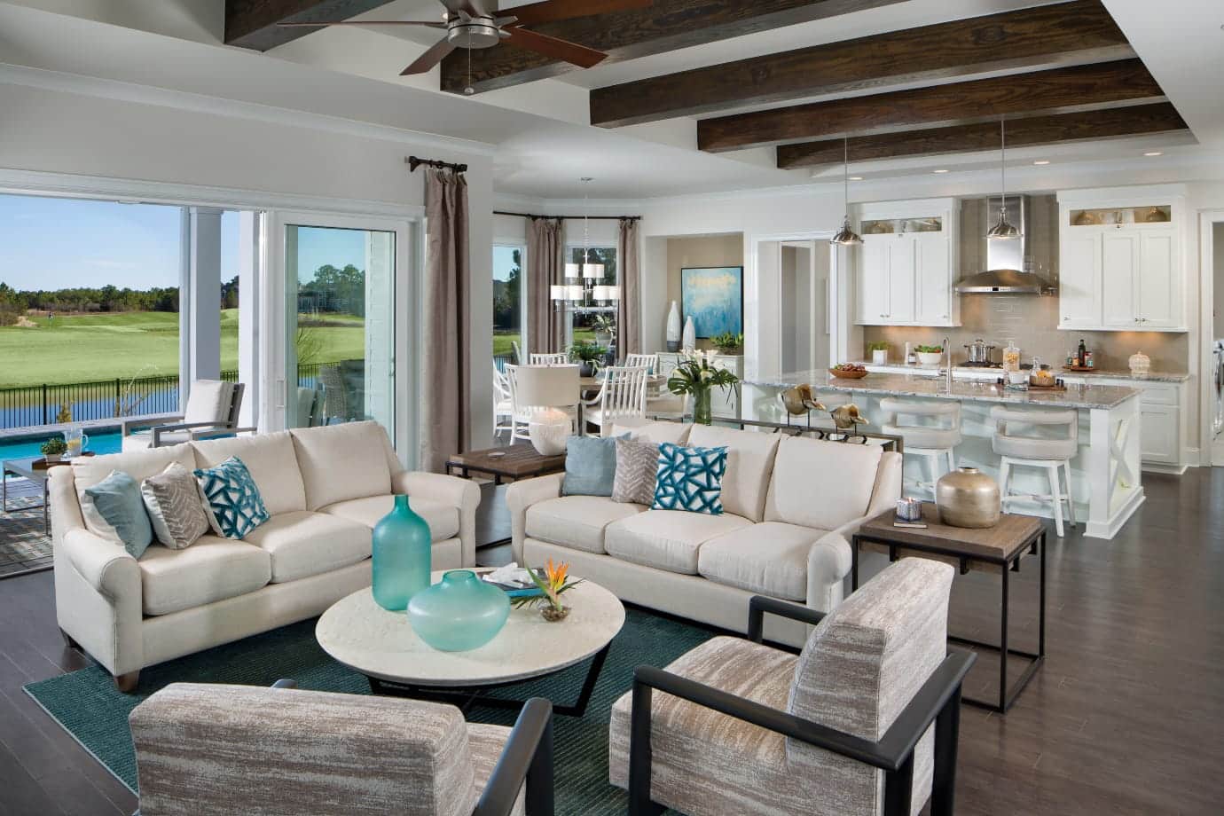 great room with wooden beams and kitchen in background