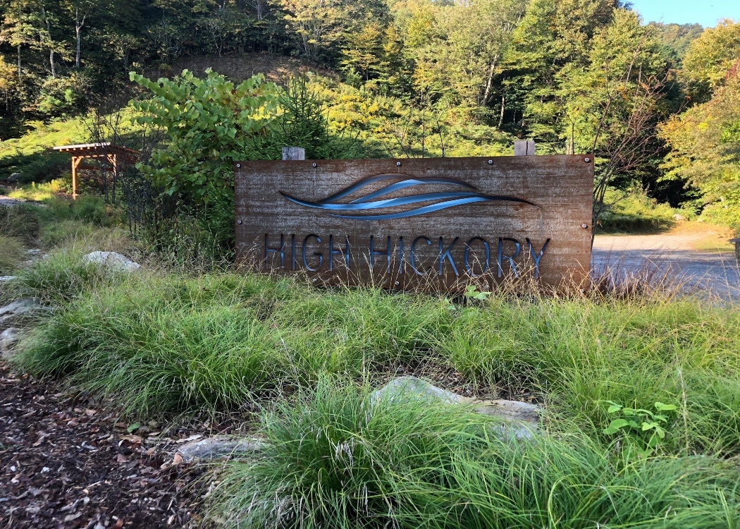 High Hickory community wooden sign covered by long grassy plants