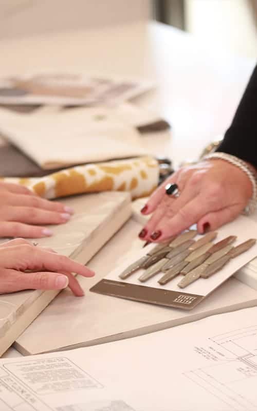 Two hands looking at floor swatches in design studio