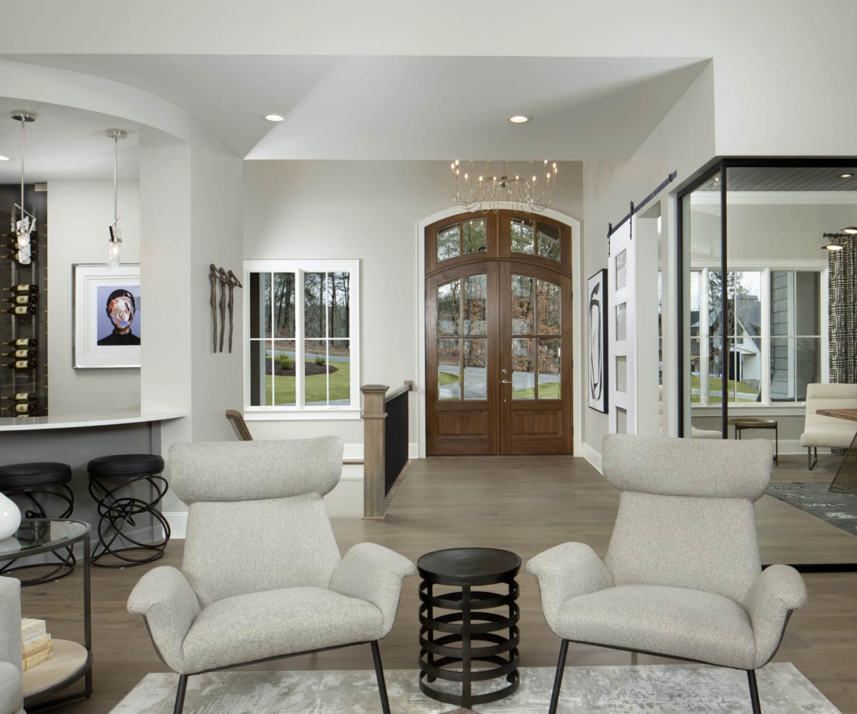 Custom Kennedy home foyer with white chairs next to clear glass door to office space on right