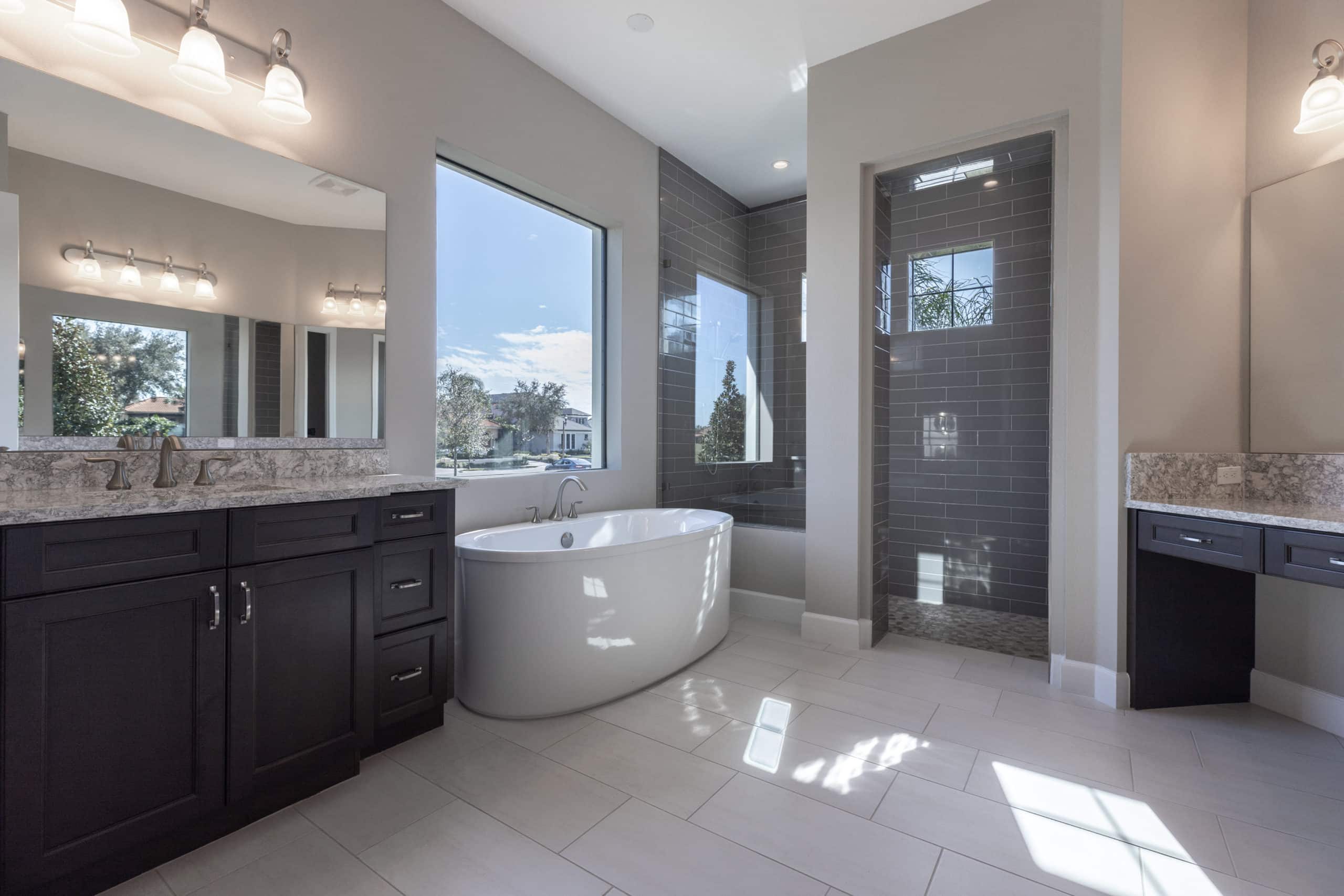 bathroom tub by window with shower and double vanity