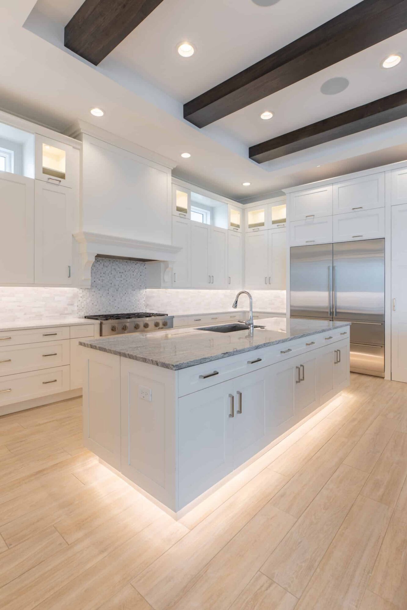 Custom hallier kitchen with wooden beam ceilings and under lit island