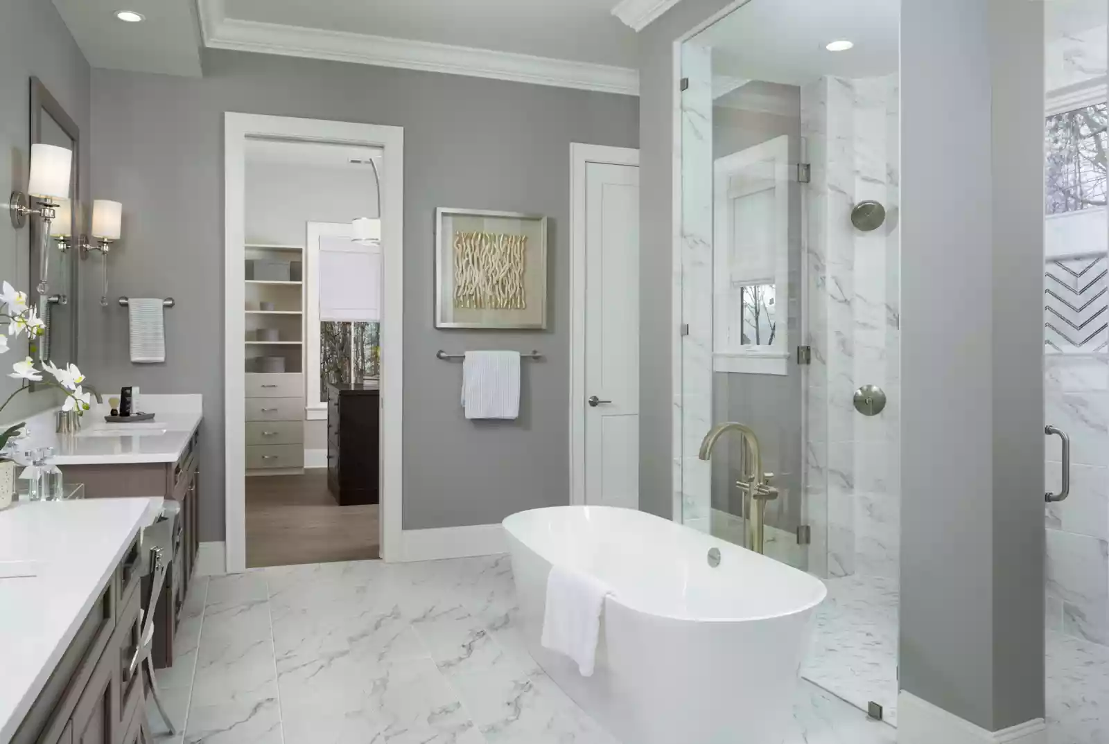 Custom Kennedy home owners bath with white marble floors, free standing bath shower, and vanity